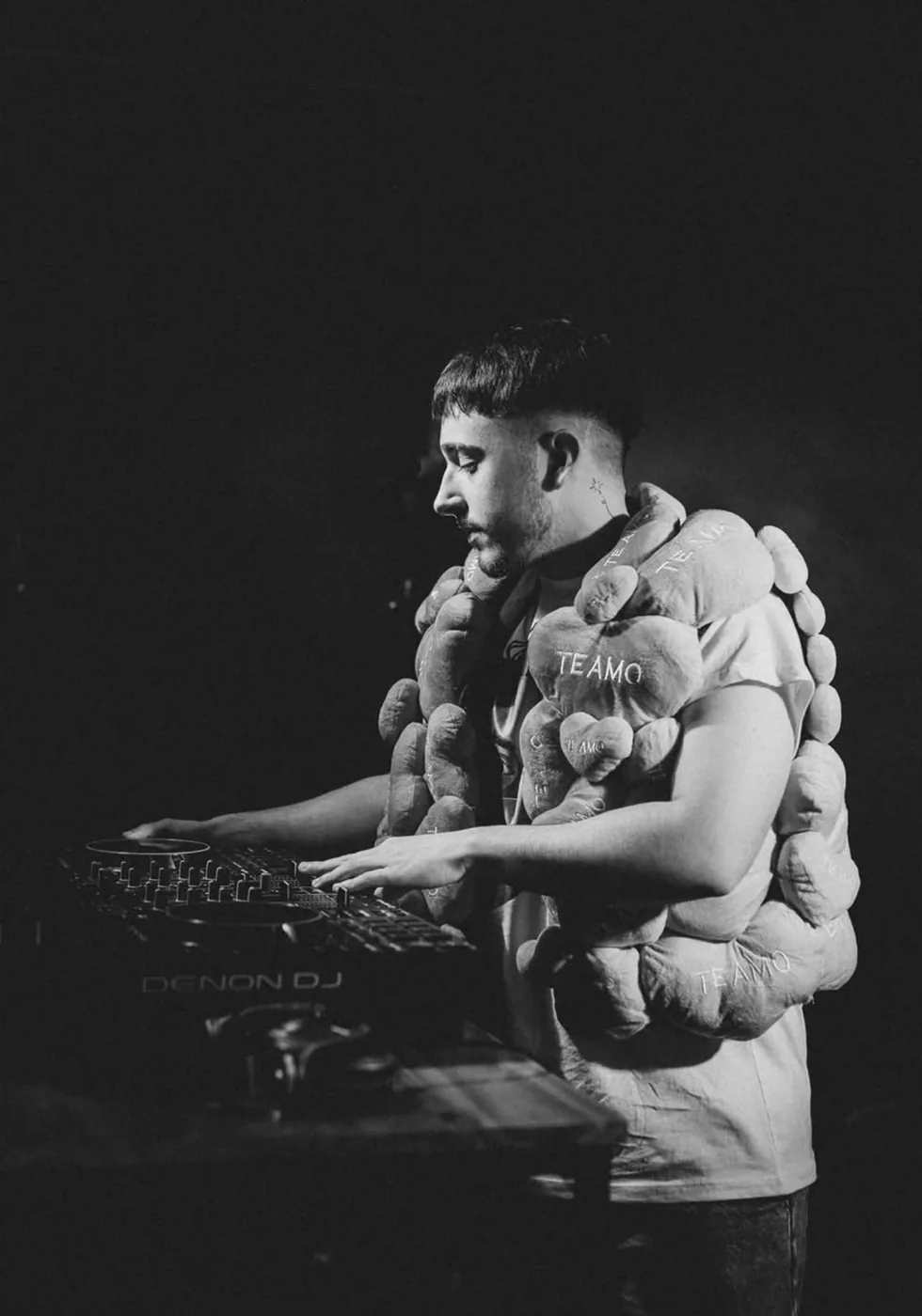 DJVALENOK de perfil sobre los decks, en blanco y negro