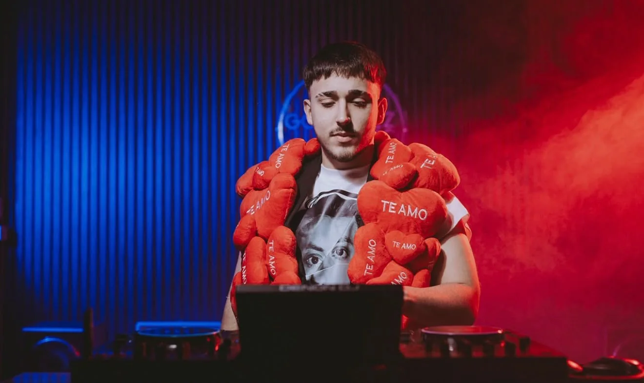 DJVALENOK en cabina con los corazones rojos al cuello, bajo luces rojas y azules